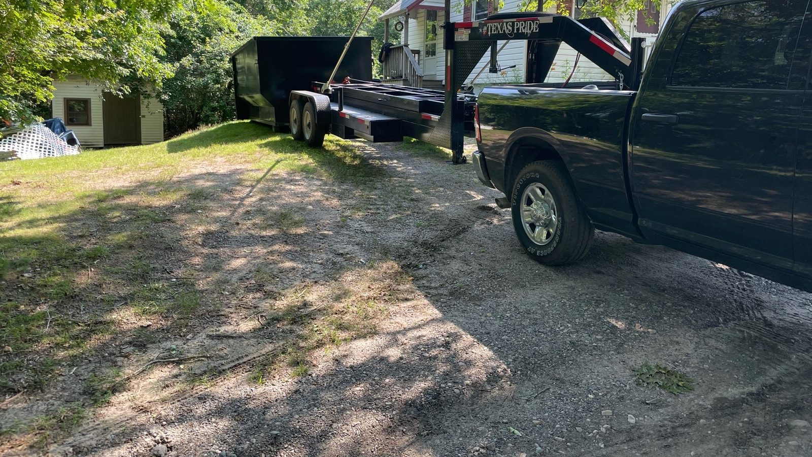 Early Plymouth Dumpster Rental delivery with a tilt trailer in a Plymouth yard