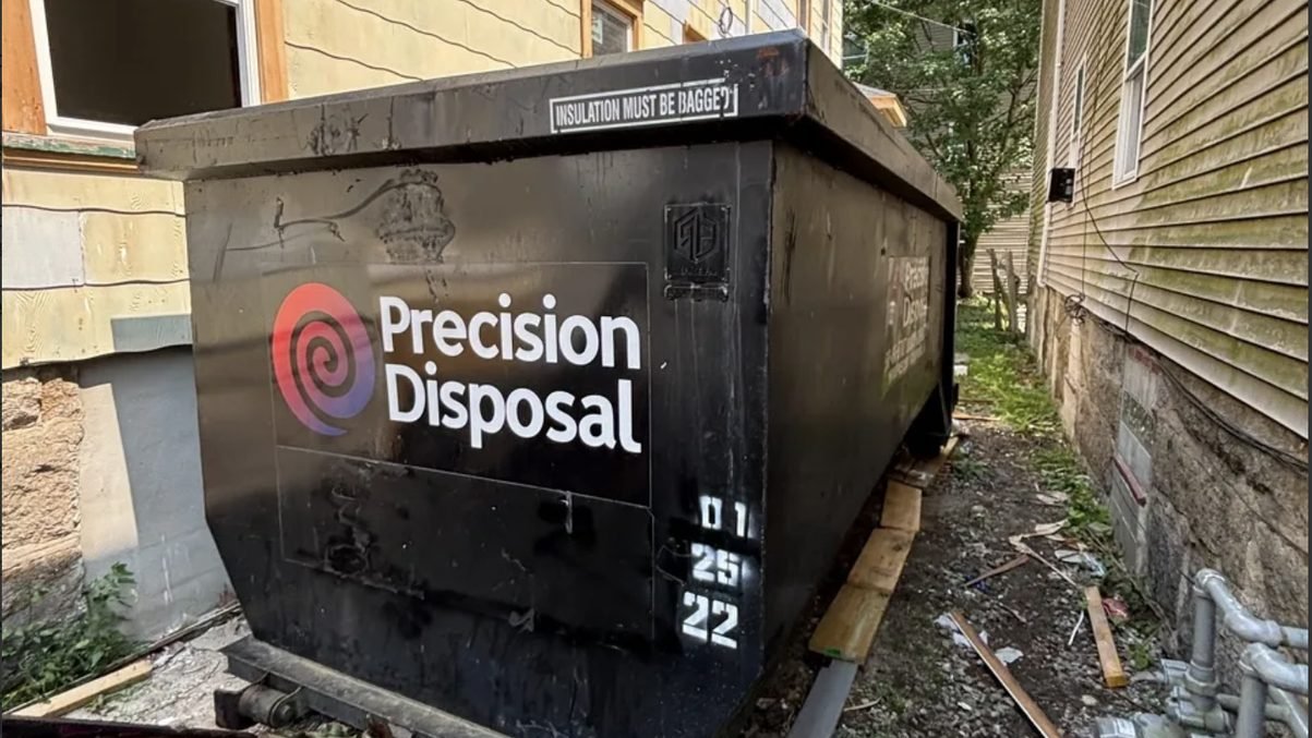 Precision Disposal roll-off dumpster beside a house