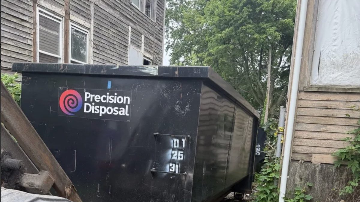 Precision Disposal roll-off dumpster beside a home