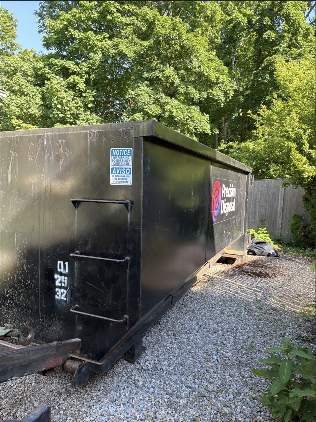 Roll-off dumpster on a gravel driveway in Plymouth, MA