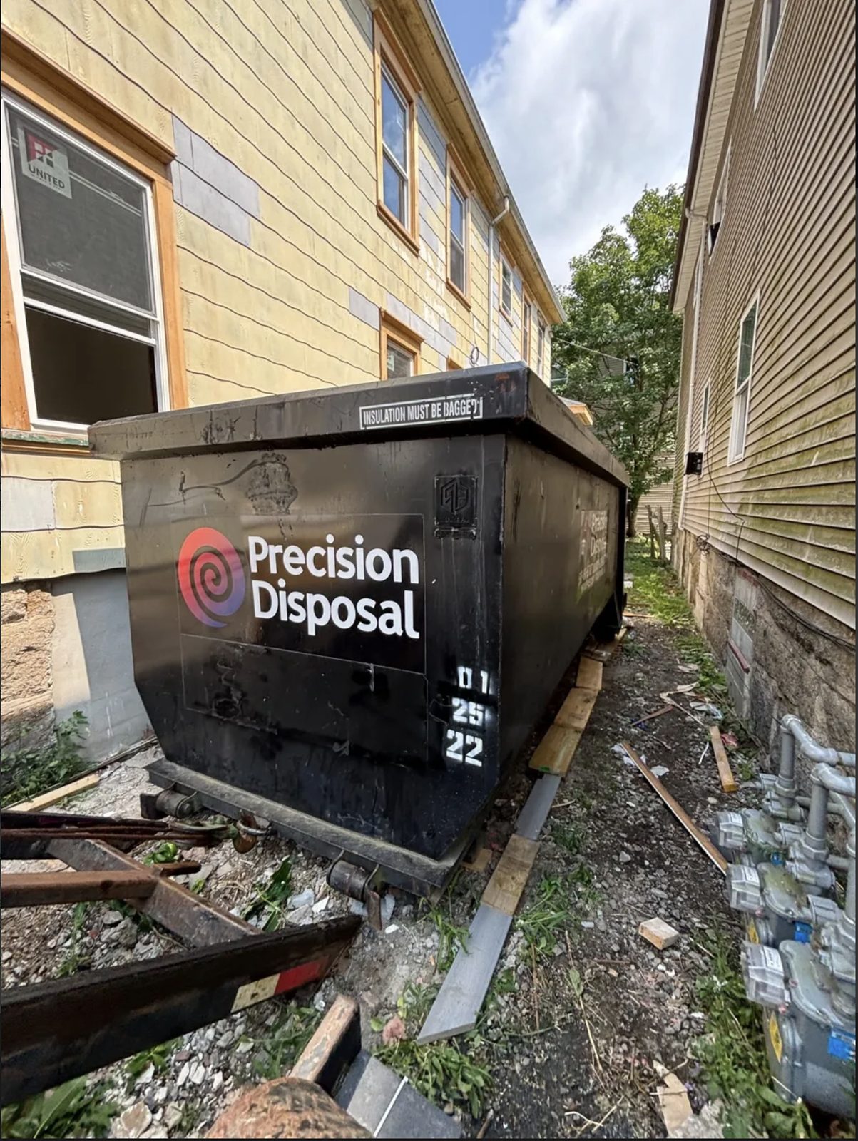 Precision Disposal roll-off dumpster set beside homes