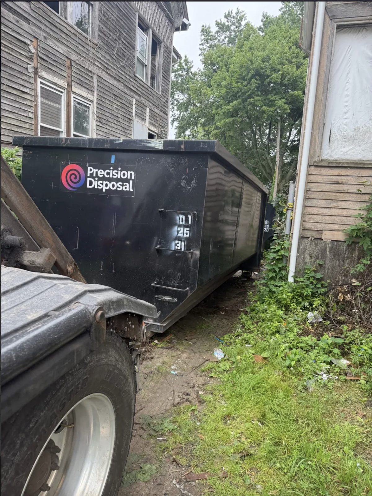 Precision Disposal roll-off dumpster beside a home
