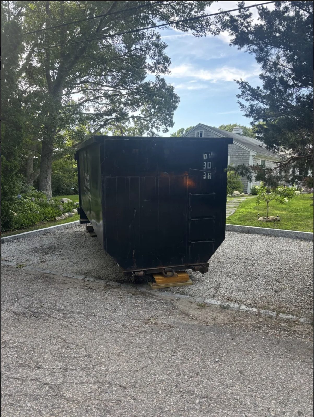 Roll-off dumpster on a gravel driveway in Falmouth, MA